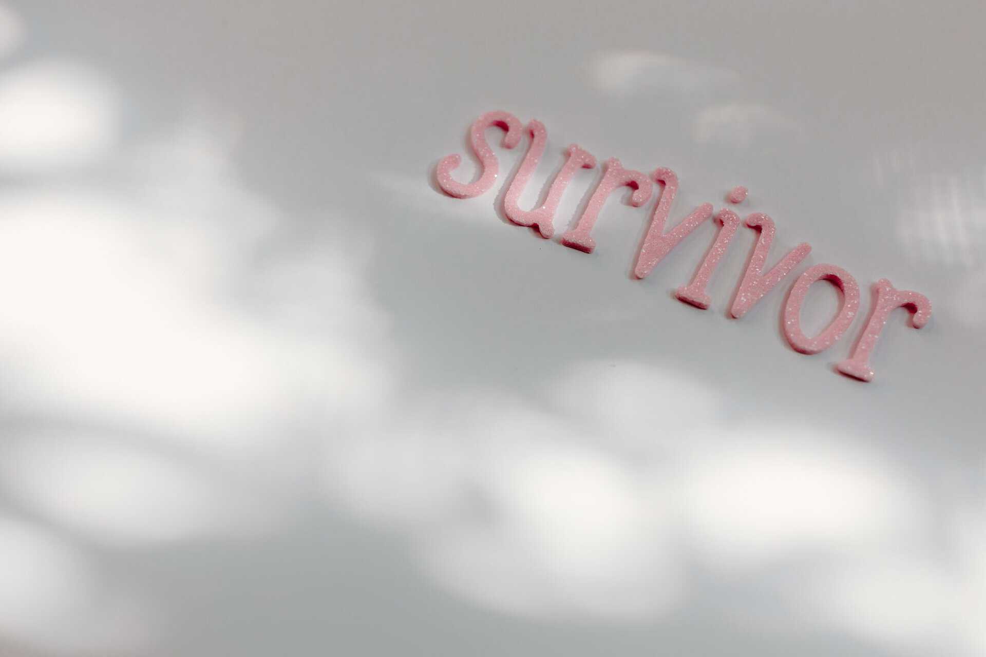 Om forfatteren Pink glittery word 'survivor' on a white surface, symbolizing awareness and resilience.